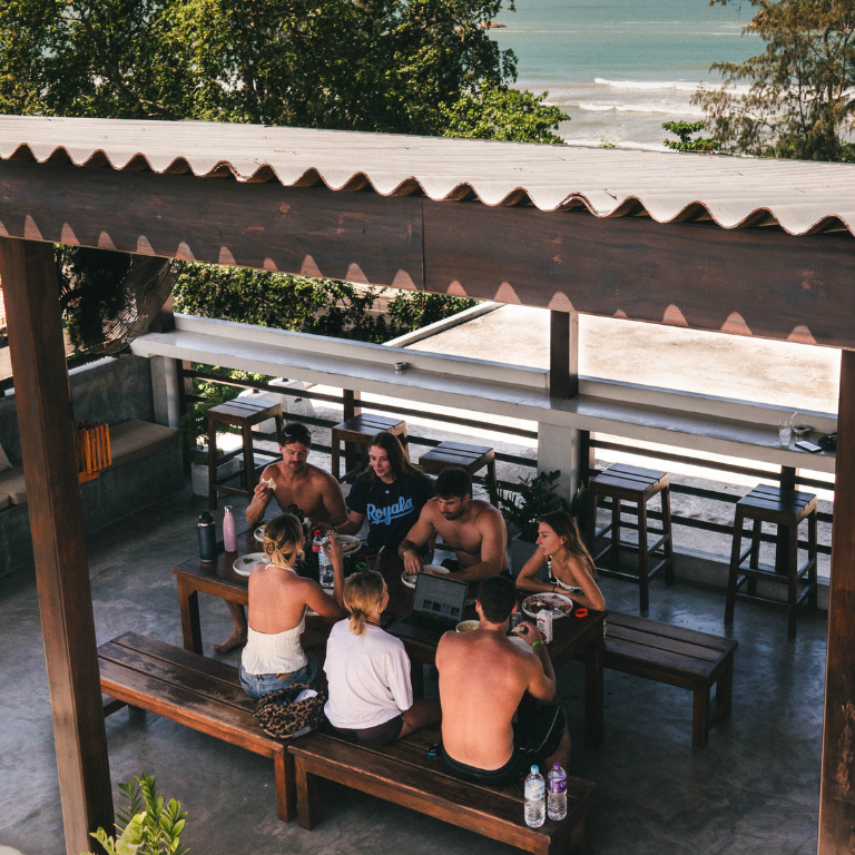 Guests sharing a family-style meal overlooking the ocean at Elsewhere Surf Camps