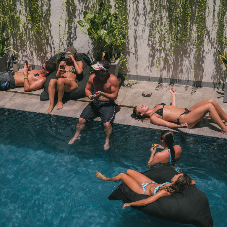 Friends relaxing together by the swimming pool at Elsewhere Surf Camps in Bali